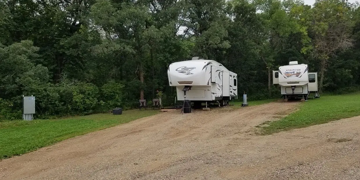 Two RVs parked in a wooded area.