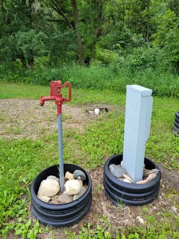 Red water pump and gray post in garden.