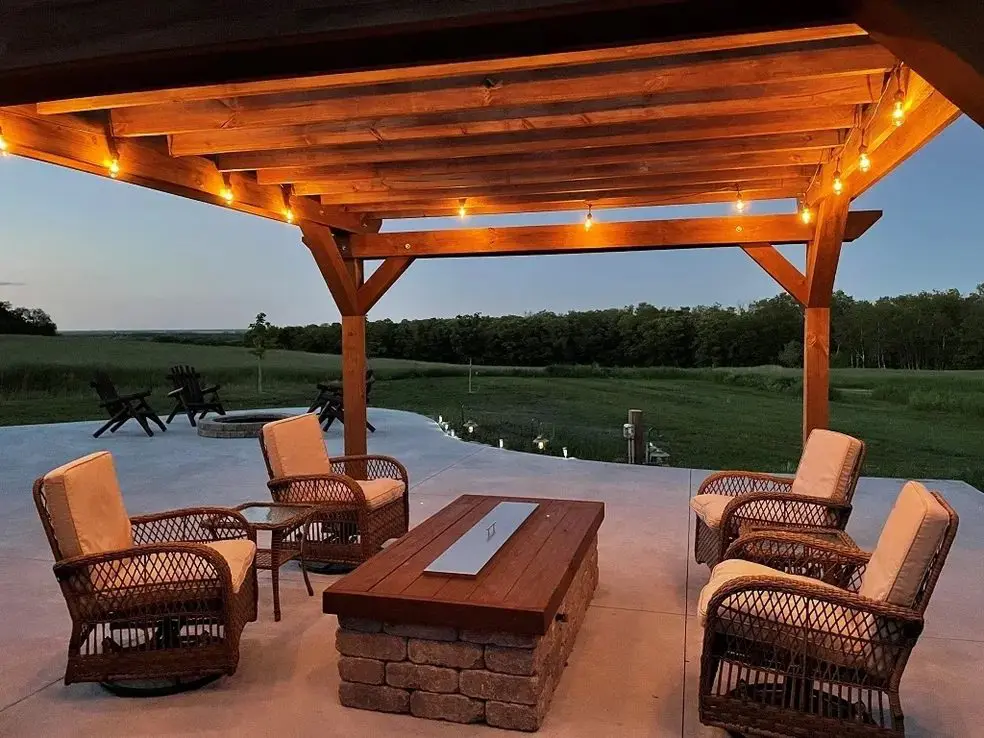 Outdoor patio with wooden pergola and chairs.